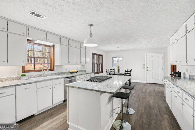 kitchen with appliances with stainless steel finishes, a center island, decorative light fixtures, white cabinetry, and sink