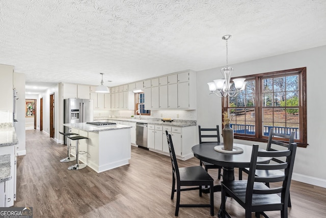 kitchen with a kitchen island, hanging light fixtures, hardwood / wood-style floors, and appliances with stainless steel finishes