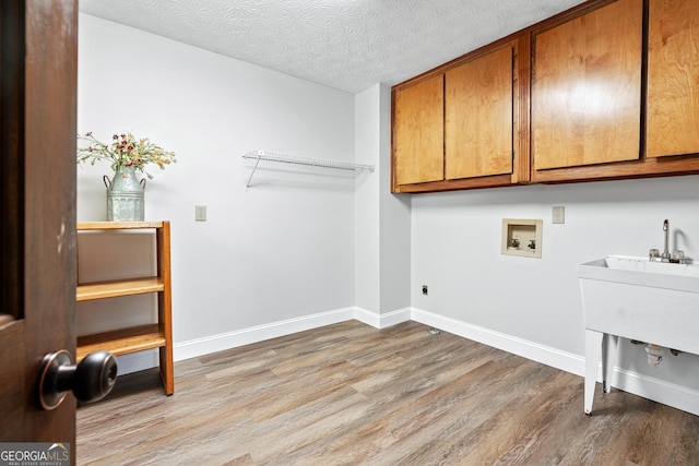 washroom featuring washer hookup, a textured ceiling, cabinets, and hardwood / wood-style floors