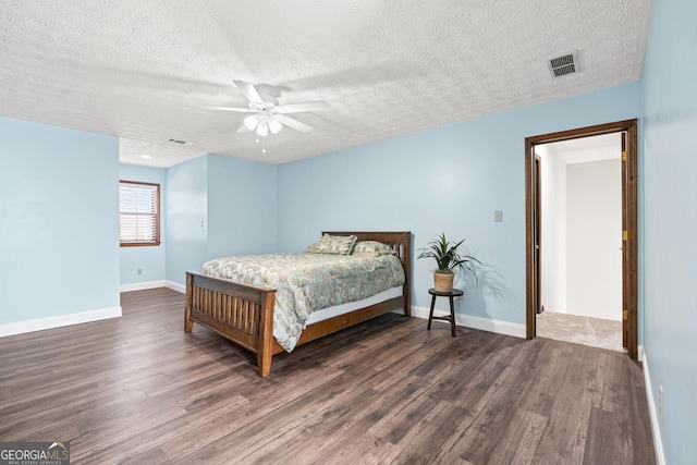 bedroom with dark wood-type flooring, a textured ceiling, and ceiling fan