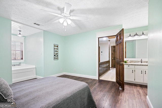 bedroom featuring ensuite bathroom, a textured ceiling, sink, dark wood-type flooring, and ceiling fan