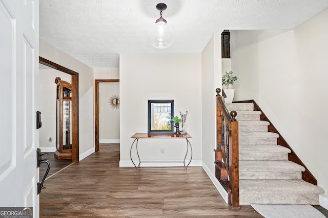 foyer entrance with hardwood / wood-style floors and a textured ceiling