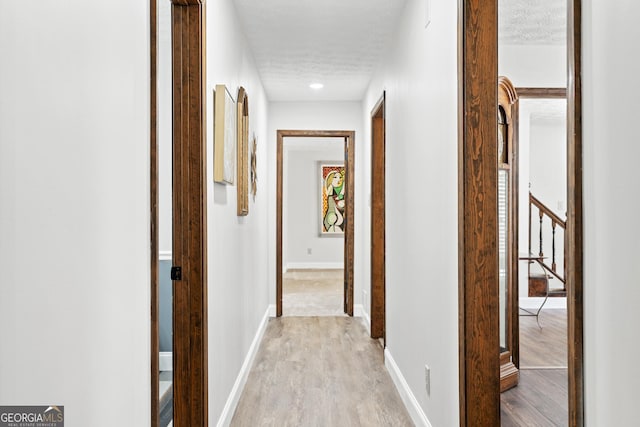 hall featuring light wood-type flooring and a textured ceiling