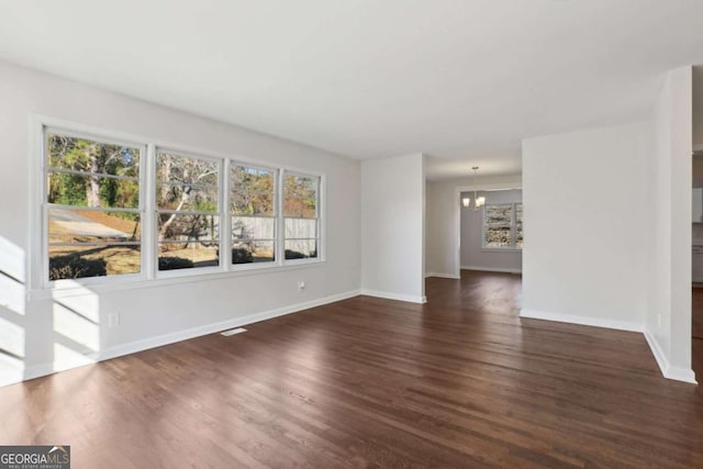 spare room featuring dark hardwood / wood-style floors and an inviting chandelier