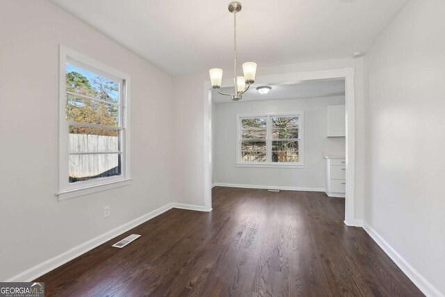 unfurnished dining area featuring dark hardwood / wood-style flooring and a notable chandelier