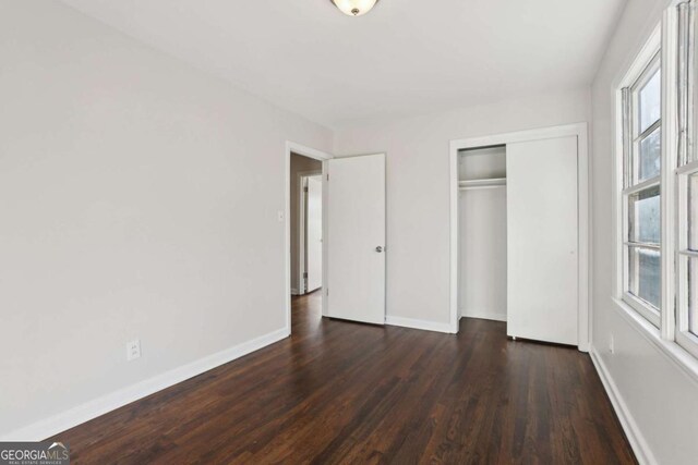 unfurnished bedroom with dark hardwood / wood-style flooring and a closet