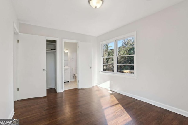 unfurnished bedroom featuring dark hardwood / wood-style flooring and ensuite bath