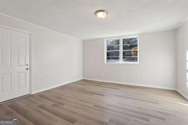 unfurnished room with a textured ceiling and light hardwood / wood-style flooring