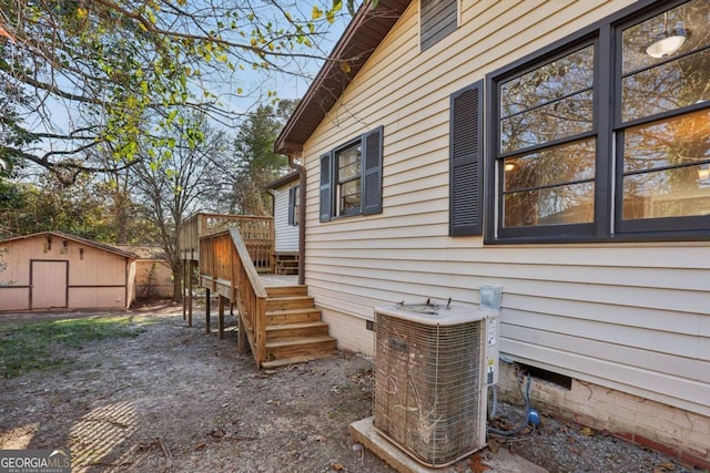 view of property exterior with a wooden deck, cooling unit, and a shed