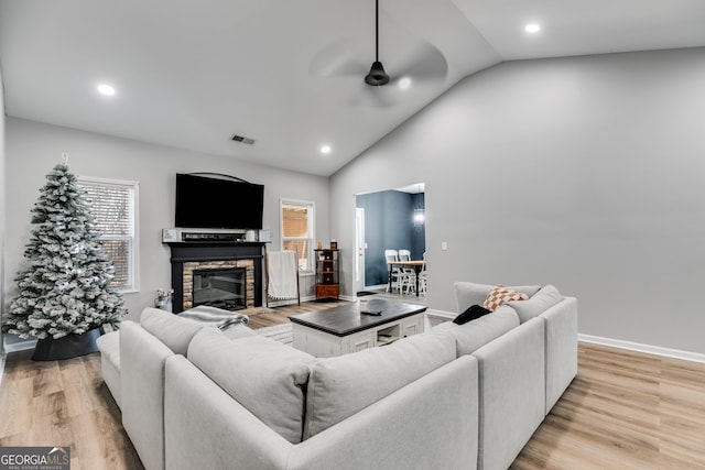 living room featuring a fireplace, light hardwood / wood-style floors, ceiling fan, and lofted ceiling