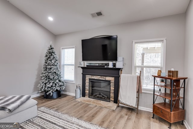 living room with a stone fireplace, plenty of natural light, and hardwood / wood-style flooring