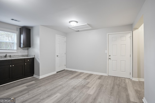 interior space featuring light stone countertops, sink, and light hardwood / wood-style flooring