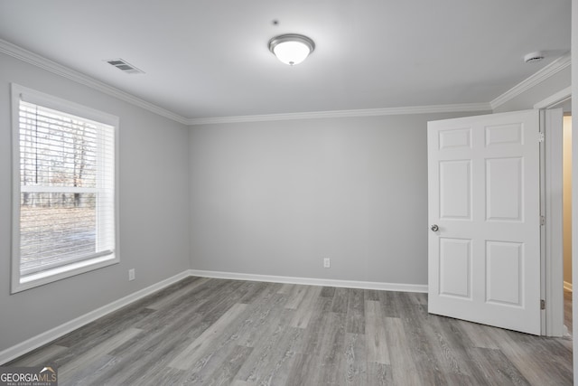 spare room featuring light hardwood / wood-style floors, a healthy amount of sunlight, and ornamental molding