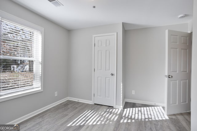 unfurnished bedroom with multiple windows and light hardwood / wood-style floors