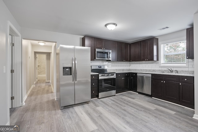 kitchen with light wood-type flooring, appliances with stainless steel finishes, dark brown cabinetry, and sink