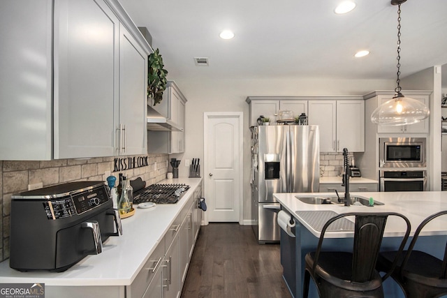 kitchen featuring hanging light fixtures, stainless steel appliances, tasteful backsplash, dark hardwood / wood-style floors, and gray cabinets