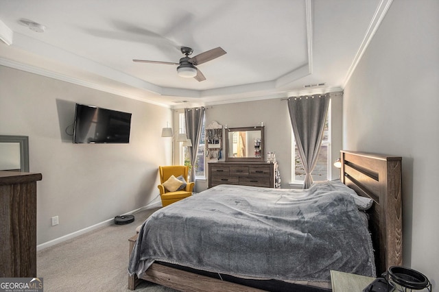 carpeted bedroom with ceiling fan, a raised ceiling, and ornamental molding