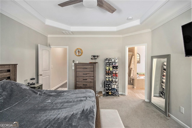 carpeted bedroom featuring a tray ceiling, ceiling fan, crown molding, and ensuite bathroom