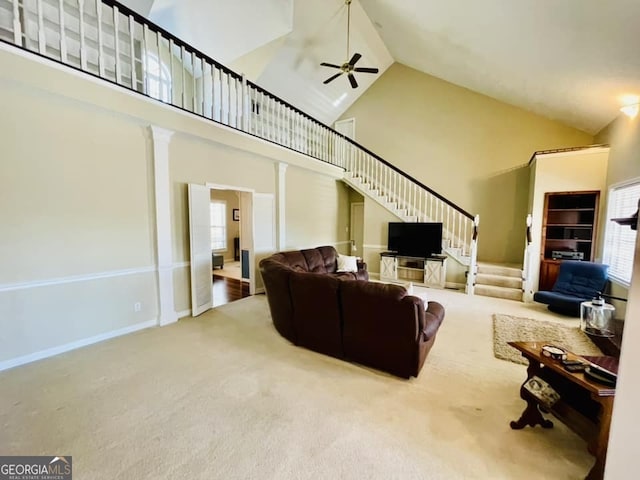 living room with ornate columns, ceiling fan, carpet flooring, and high vaulted ceiling