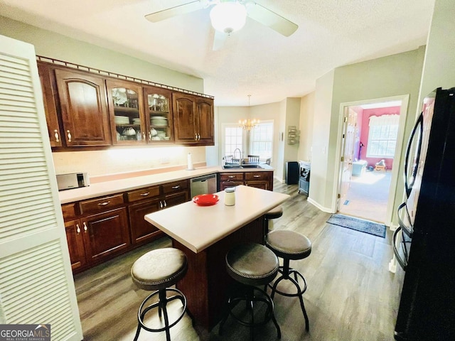 kitchen with a kitchen bar, black fridge, light hardwood / wood-style flooring, dishwasher, and pendant lighting