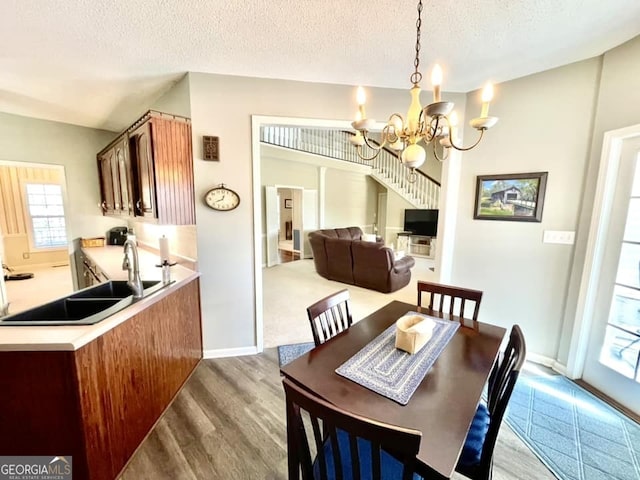 dining room featuring sink, a textured ceiling, an inviting chandelier, and light hardwood / wood-style floors