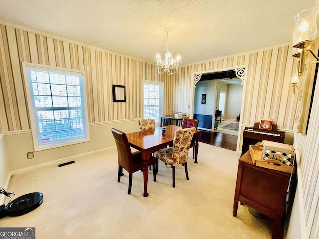 dining room with ornamental molding, carpet, an inviting chandelier, and a textured ceiling