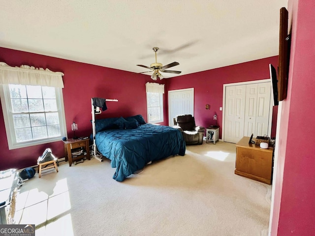 carpeted bedroom featuring multiple closets and ceiling fan