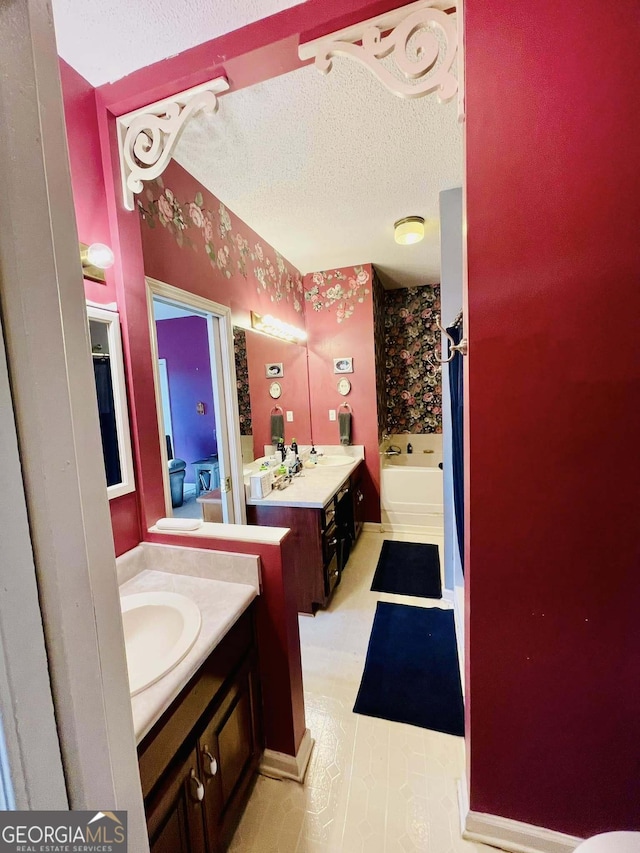 bathroom with vanity, a bathing tub, and a textured ceiling