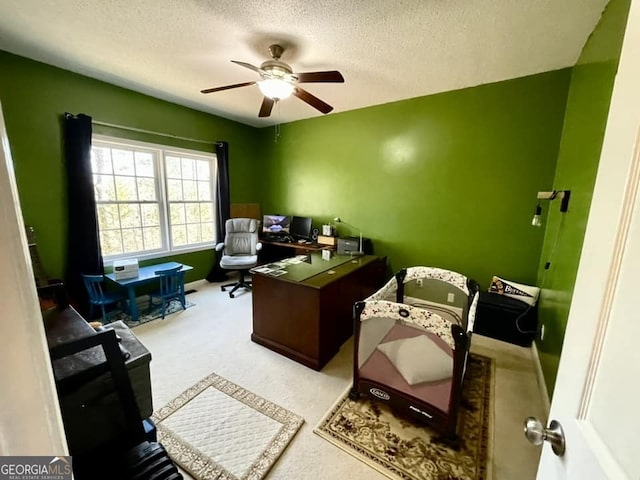 carpeted office space featuring ceiling fan and a textured ceiling