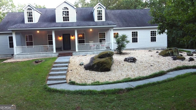 cape cod house featuring a porch and a front yard