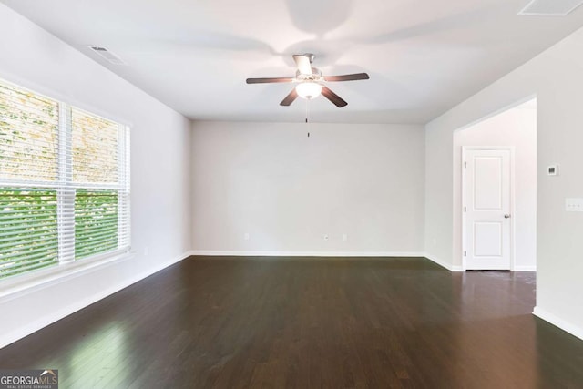 spare room featuring dark hardwood / wood-style floors, ceiling fan, and a wealth of natural light