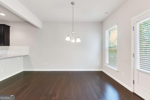 unfurnished dining area with dark hardwood / wood-style floors, an inviting chandelier, and plenty of natural light