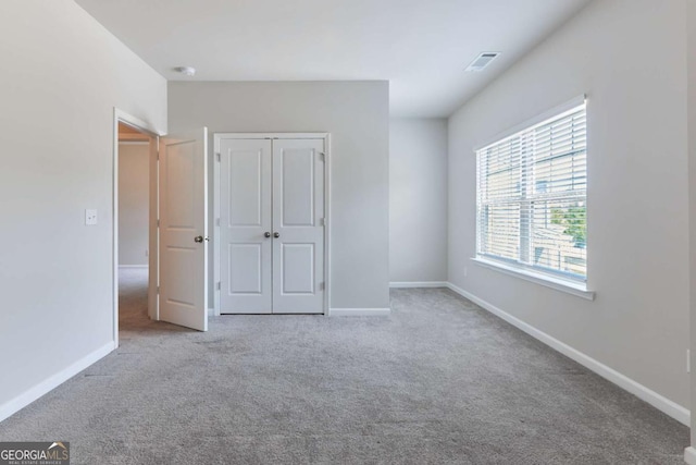 unfurnished bedroom featuring light colored carpet and a closet