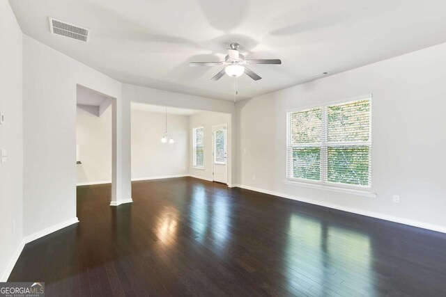 spare room with ceiling fan with notable chandelier and dark hardwood / wood-style floors