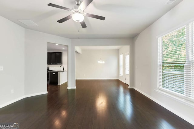 unfurnished living room with dark hardwood / wood-style flooring and ceiling fan with notable chandelier