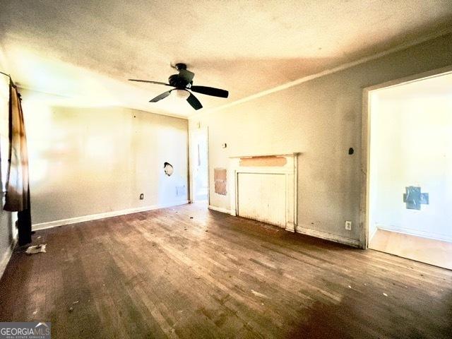 unfurnished living room with ceiling fan, crown molding, a textured ceiling, and dark hardwood / wood-style flooring