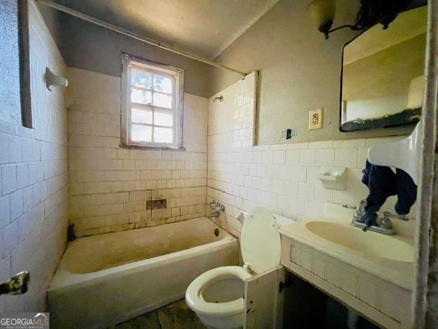 full bathroom with tiled shower / bath, tile walls, vanity, and toilet