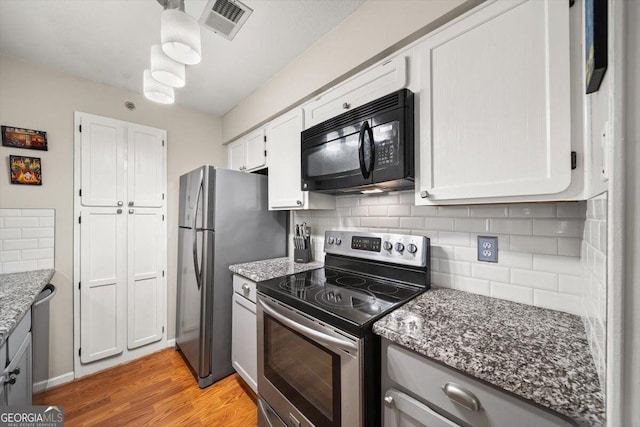 kitchen with backsplash, dark stone countertops, light hardwood / wood-style floors, white cabinetry, and stainless steel appliances