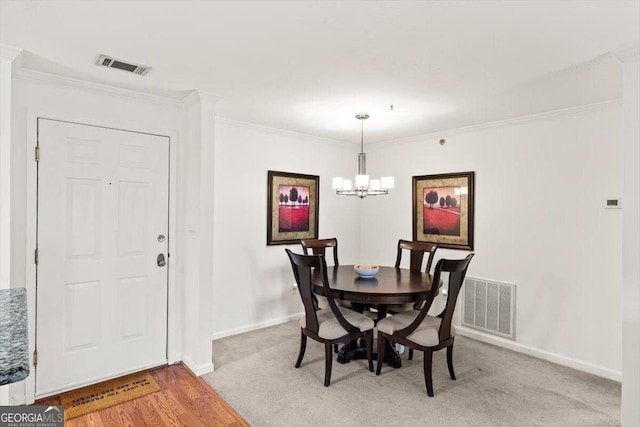 dining room with crown molding, light colored carpet, and a chandelier