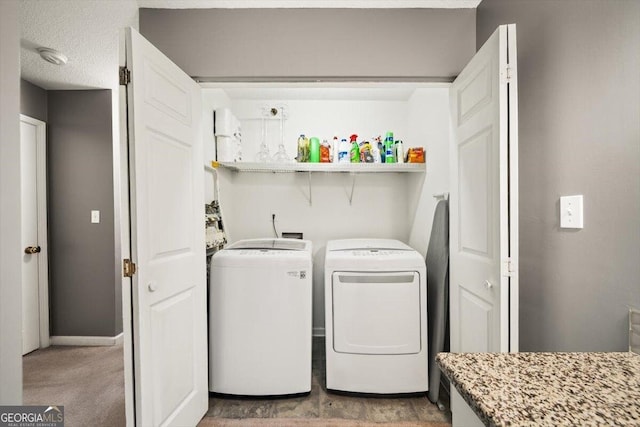 clothes washing area featuring a textured ceiling, light carpet, and washing machine and clothes dryer