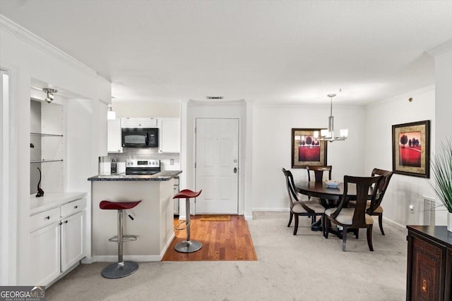 kitchen with white cabinetry, stainless steel electric range oven, an inviting chandelier, decorative light fixtures, and a kitchen bar