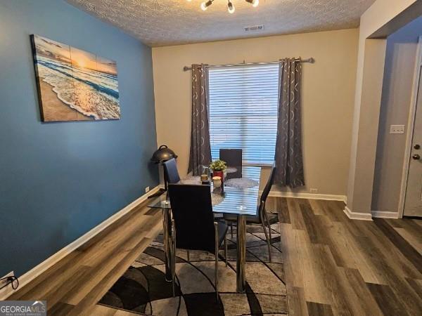 dining space with dark hardwood / wood-style flooring and a textured ceiling