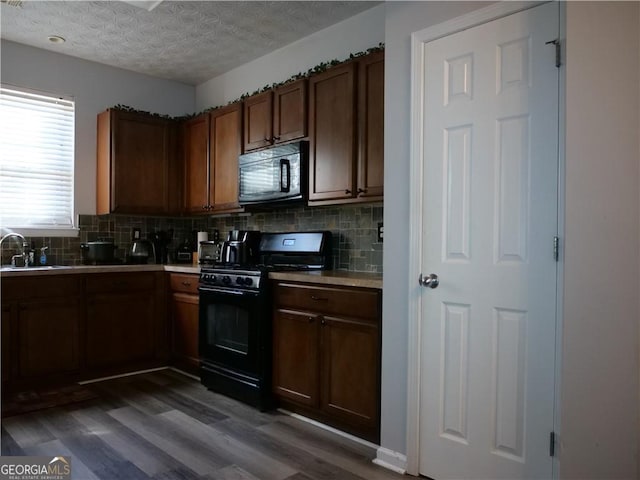 kitchen with black appliances, sink, decorative backsplash, a textured ceiling, and wood-type flooring