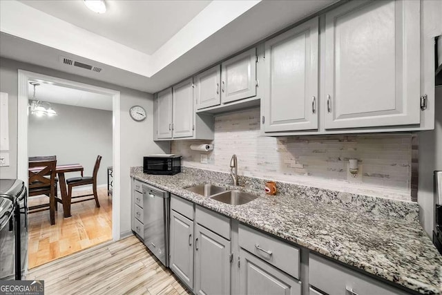 kitchen with sink, an inviting chandelier, black electric range oven, stainless steel dishwasher, and light hardwood / wood-style floors