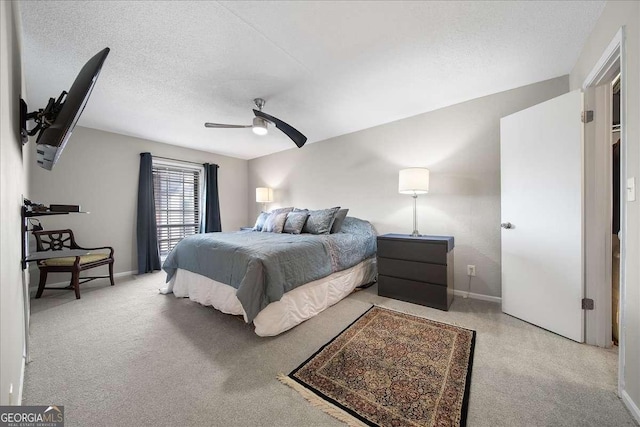 bedroom with ceiling fan, a textured ceiling, and light carpet