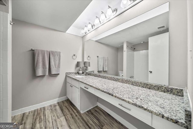 bathroom featuring walk in shower, hardwood / wood-style flooring, vanity, and toilet