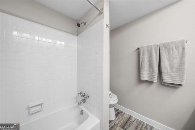 bathroom with hardwood / wood-style floors, toilet, and tiled shower / bath