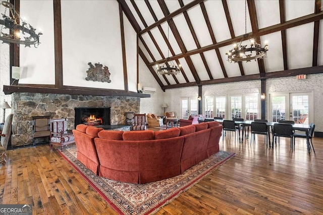 living room with a stone fireplace, high vaulted ceiling, wood-type flooring, and an inviting chandelier