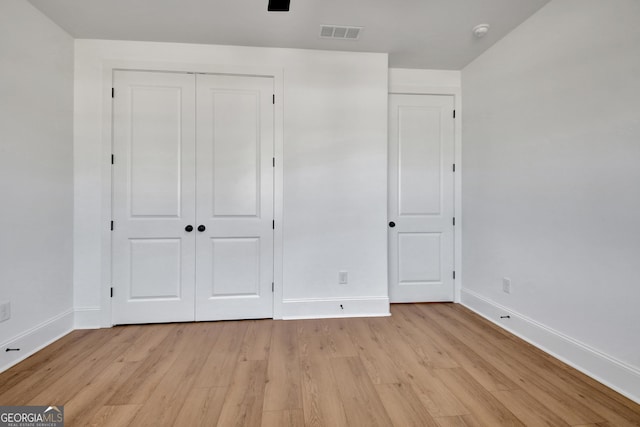 unfurnished bedroom with a closet and light wood-type flooring