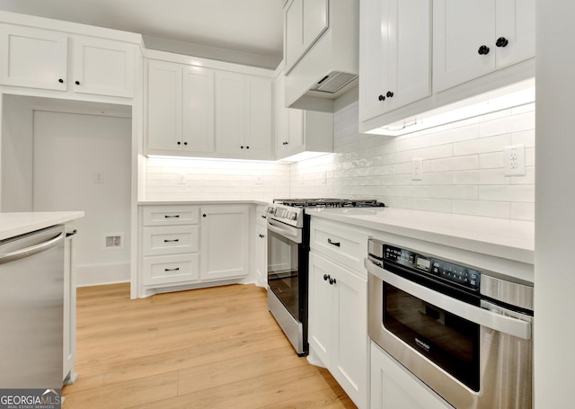 kitchen with appliances with stainless steel finishes, light hardwood / wood-style floors, white cabinetry, and tasteful backsplash